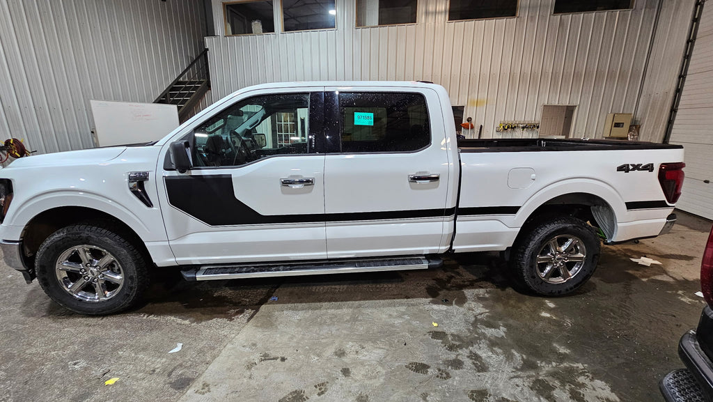 A white Ford F-150 4x4 pickup truck parked inside a warehouse or garage, shown from a side profile view.